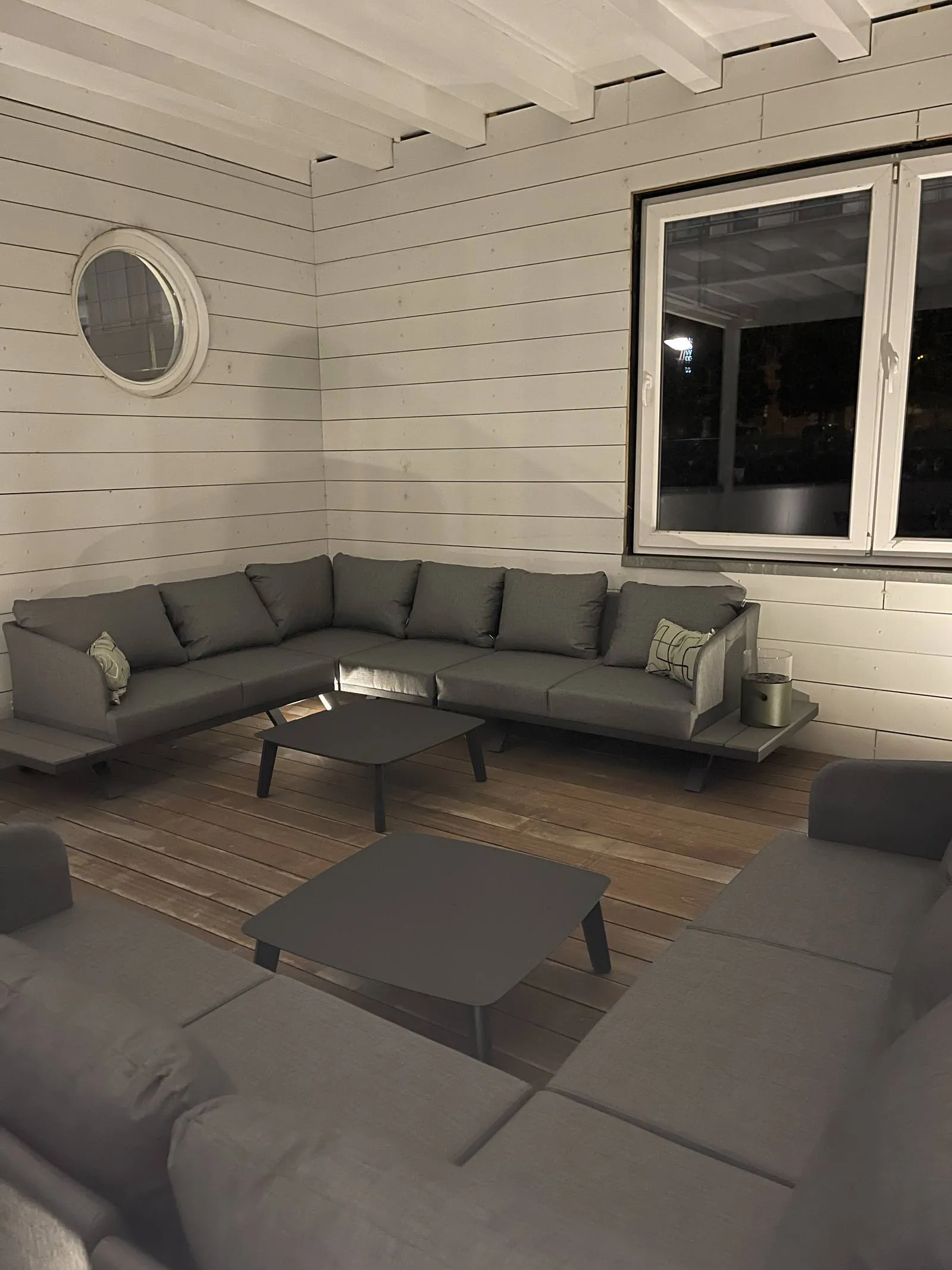 Graue Lounge-Sitzgruppe mit Couchtisch unter dem Dach der Terrasse