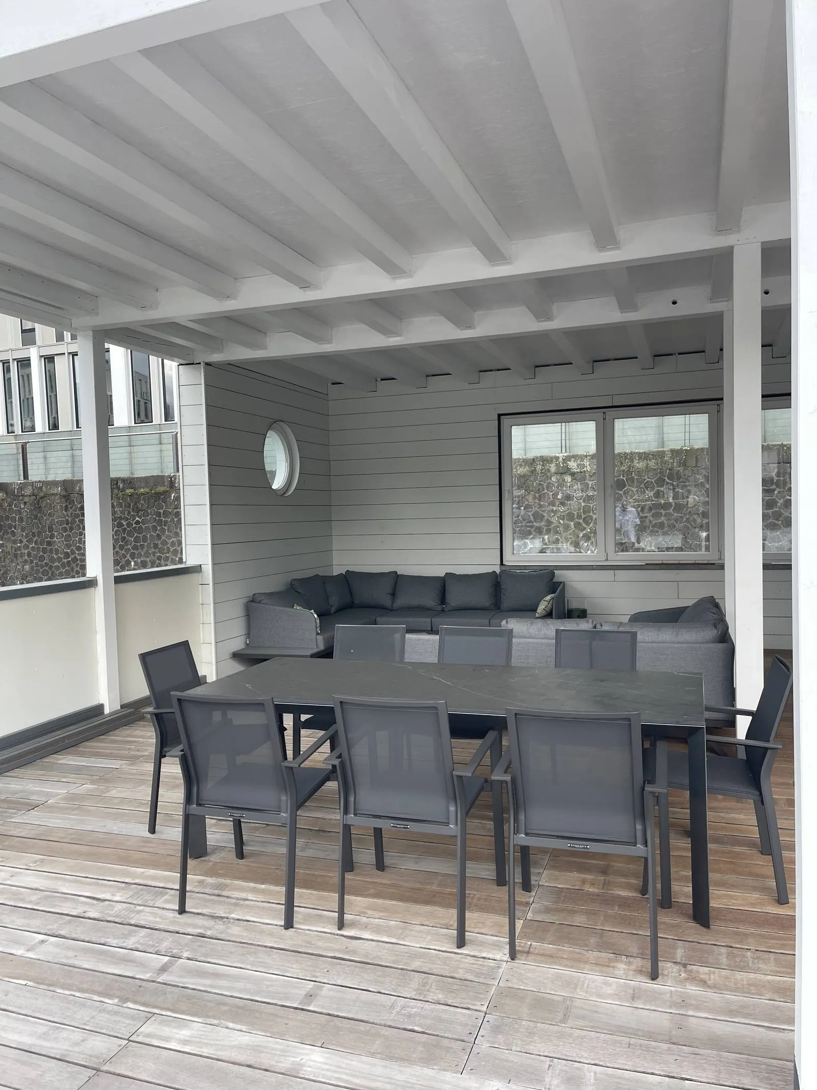 Langer dunkler Esstisch mit Stühlen auf der Holzterrasse